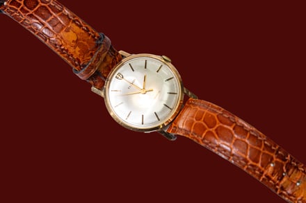 vintage watch with brown strap on brown hero background